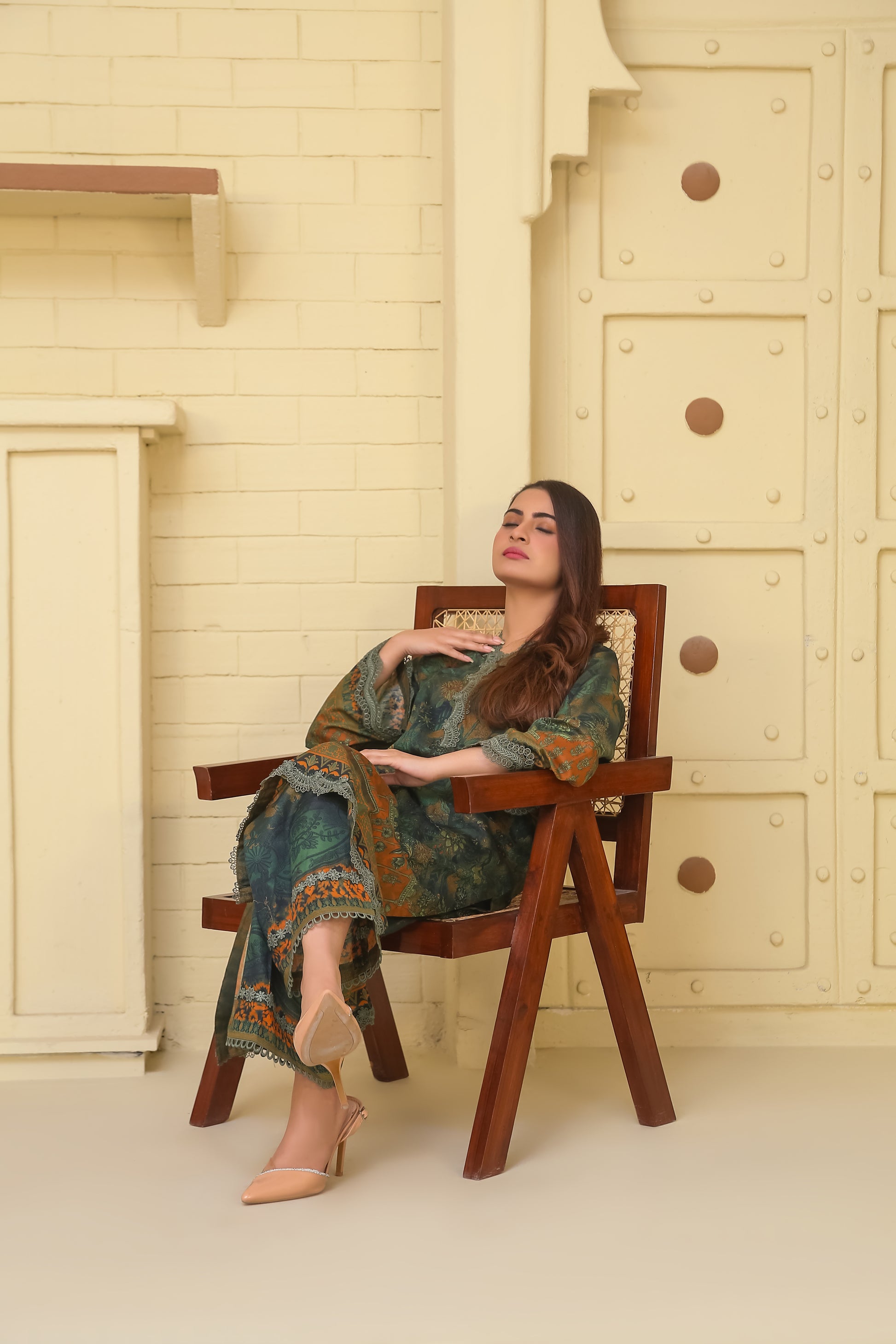 Woman relaxing in a chair wearing Saadia Ahmed LWSU-25P203 2-Pcs Printed Lawn outfit with vibrant floral design